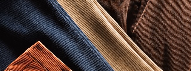 Nahaufnahme mehrerer Cordstoffe in verschiedenen Farben: Blau, Beige, Braun und Orange.