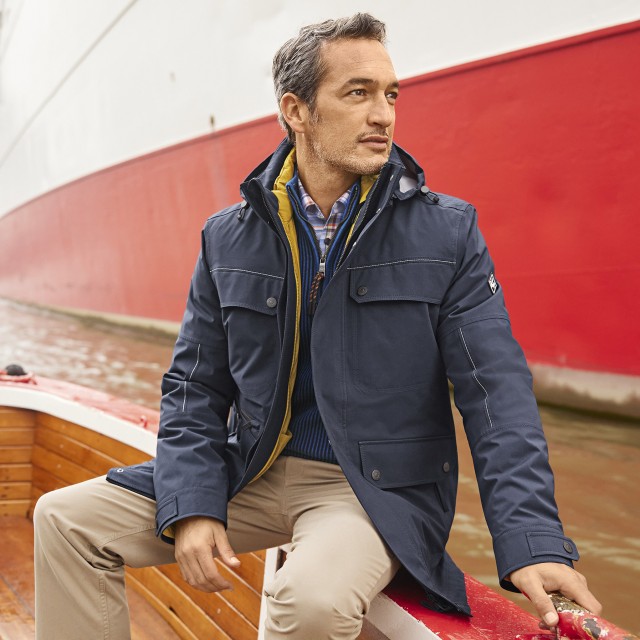Ein Herr sitzt mit einer Walbusch Jacke auf einem kleinen Boot.