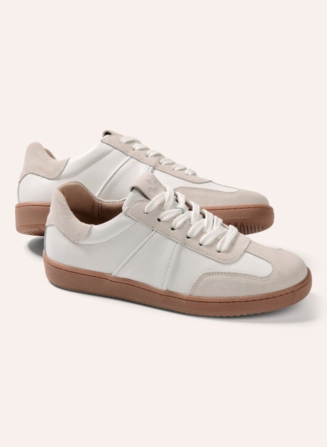 Ein Paar weiße Sneaker mit beigen Wildlederdetails und brauner Sohle steht vor hellem Hintergrund. Ein Paar weiße Sneaker mit beigen Wildlederdetails und brauner Sohle steht vor hellem Hintergrund.