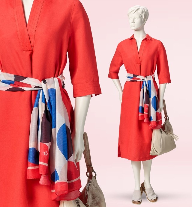 Puppe trägt eine rotes Kleid mit einem gepunkteten Schal, dazu eine beige Handtasche und passende Schuhe