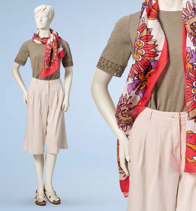 Puppe trägt ein grünes T-Shirt mit einem gemusterten Schal, dazu einen beigen Hosenrock und Sandalen