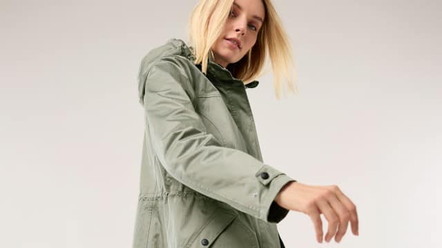 Eine Frau trägt eine hellgrüne Jacke mit Kapuze und bewegt leicht ihren Arm nach vorn. Eine Frau trägt eine hellgrüne Jacke mit Kapuze und bewegt leicht ihren Arm nach vorn.