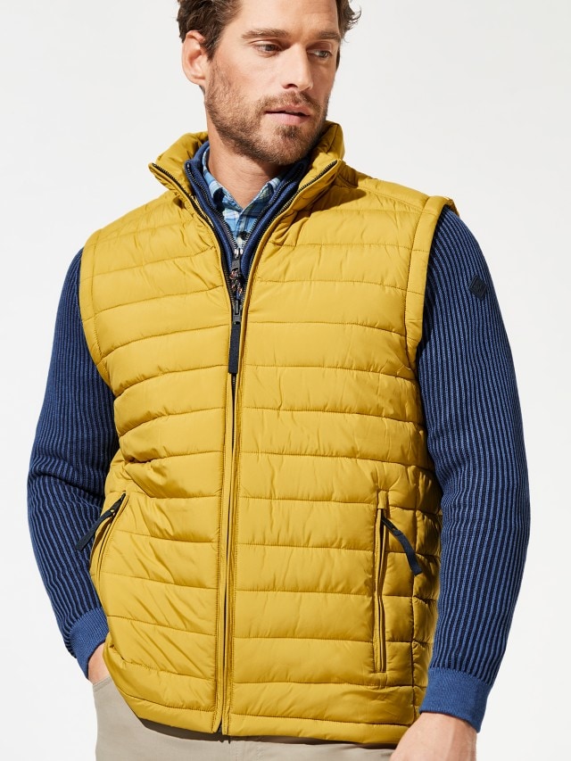 Mann trägt gelbe Weste über blauer Jacke