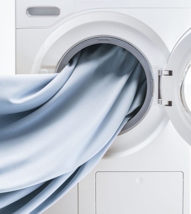 Geöffnete Waschmaschine mit einem hellblauen Stoff.