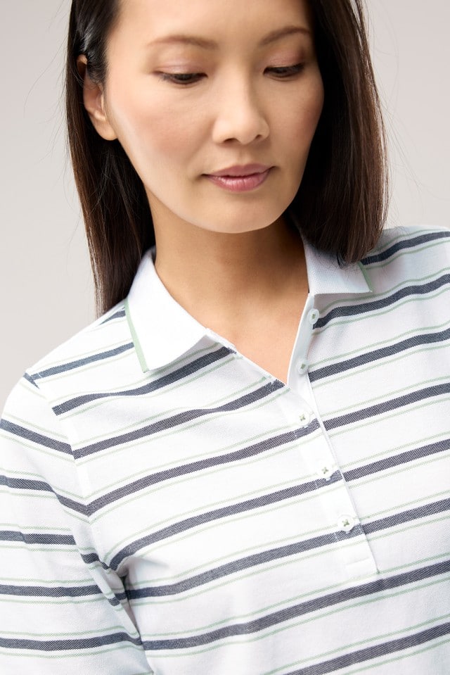 Eine Frau trägt ein gestreiftes Extraglatt Polo in Salbei.