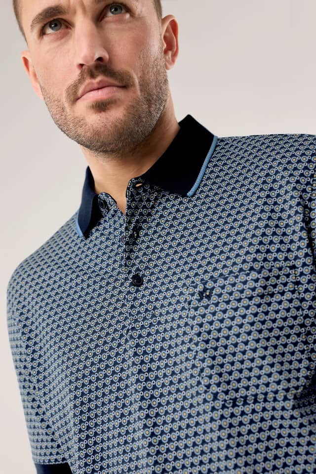 Ein Mann trägt ein Extraglatt-Polo Bicolor in Druck Minimal.
