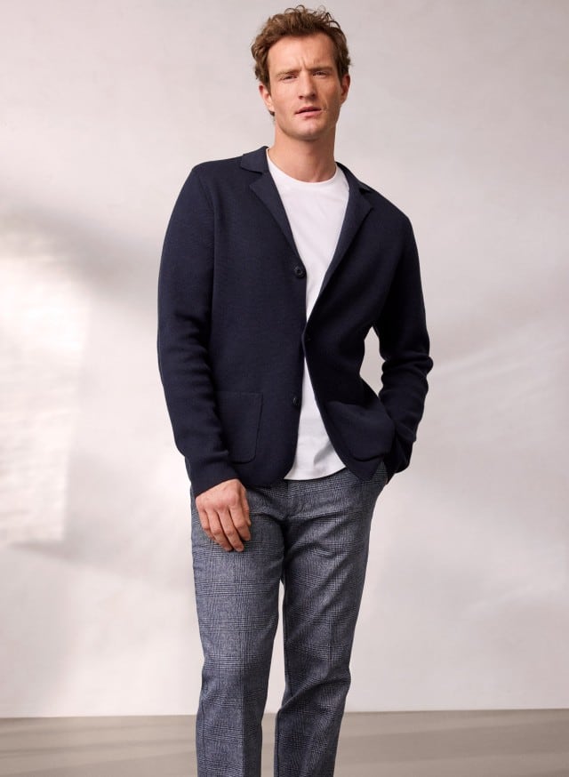 Ein Mann trägt den Milano Rib Blazer in Navy, darunter ein weißes Shirt und dazu eine Cool-Wool Chino in Marine Kariert.