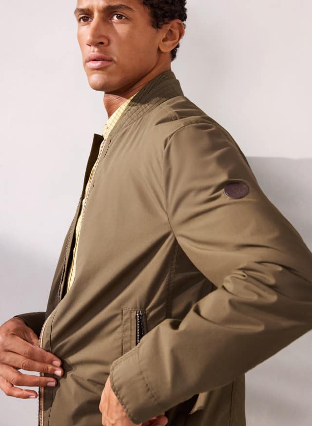 Ein Mann trägt einen Baumwoll Leichtblouson in Oliv.
