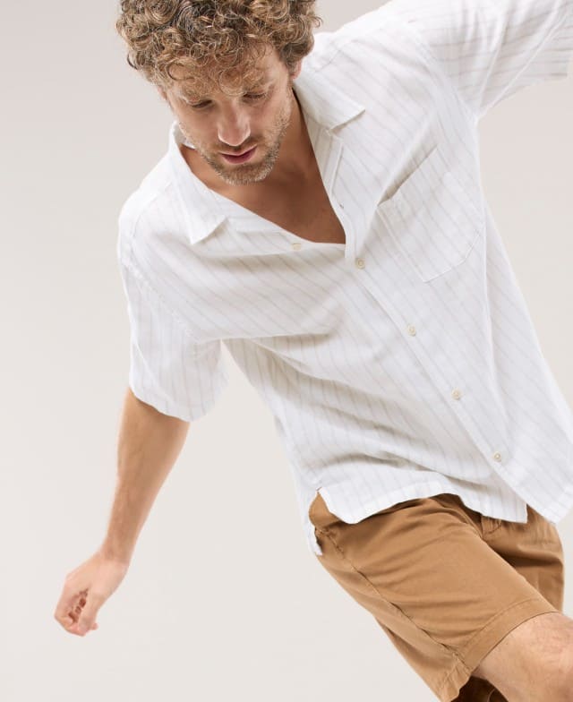 Ein Mann trägt ein weißes Leinen-Hemd und ein Shorts in Beige.