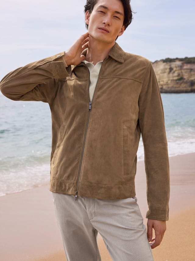 Ein Mann trägt eine hellbraune Veloursjacke zu einem hellen Shirt und grauen Hosen, was hochwertig, natürlich und ruhig‑entspannt wirkt.