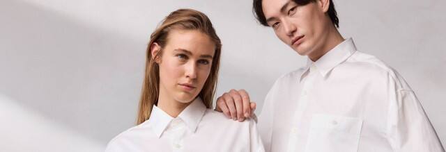 Ein Mann und eine Frau stehen nebeneinander und tragen beide weiße Hemden.