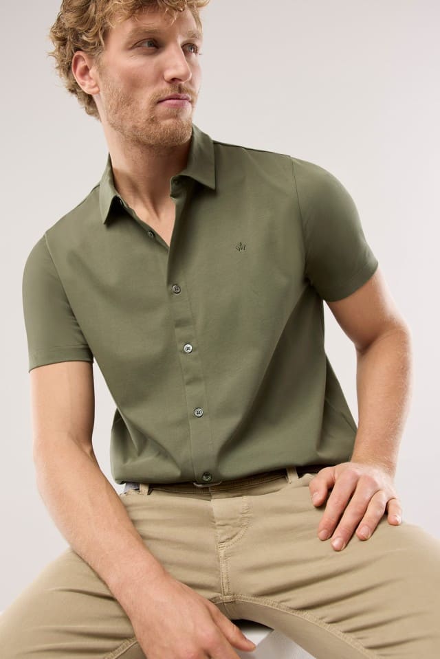 Ein Mann trägt ein Shirtpolo in Khaki, dazu eine Jeans in Beige. Ein Mann trägt ein Shirtpolo in Khaki, dazu eine Jeans in Beige.