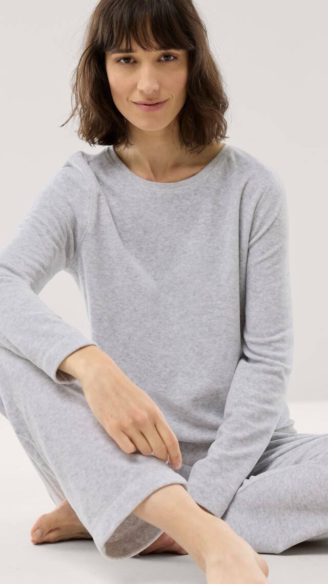 Ein Frau sitzt auf dem Boden und trägt einen Nicki Kuschel Anzug in hellgrau.
