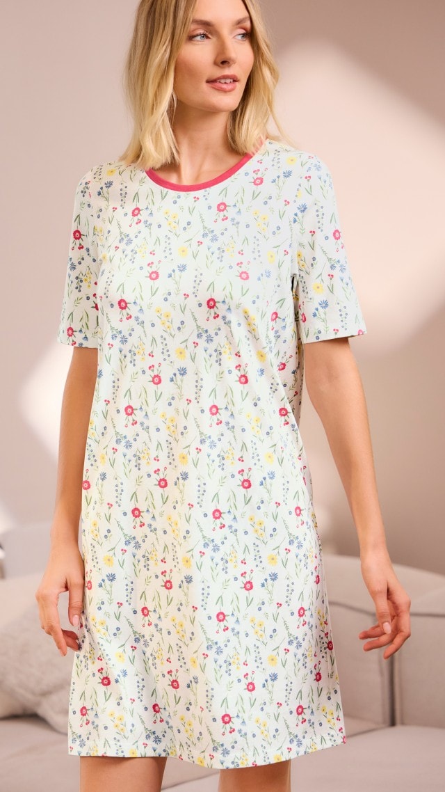 Blonde Frau stehend vor einer Couch in Schlafshirt