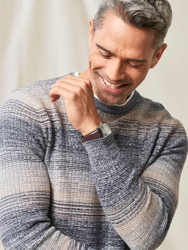 Glücklicher Mann in hochwertiger Strickkleidung.