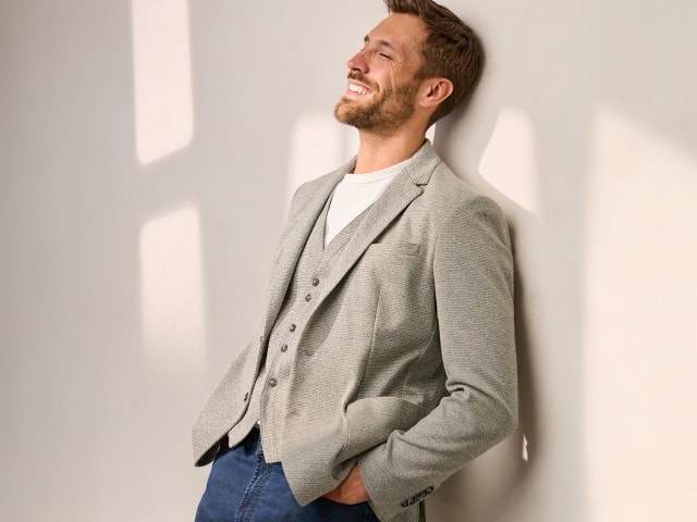 Ein Mann trägt ein Struktur-Sakko, mit passender Weste und weißem Hemd. Dazu eine Jeans.