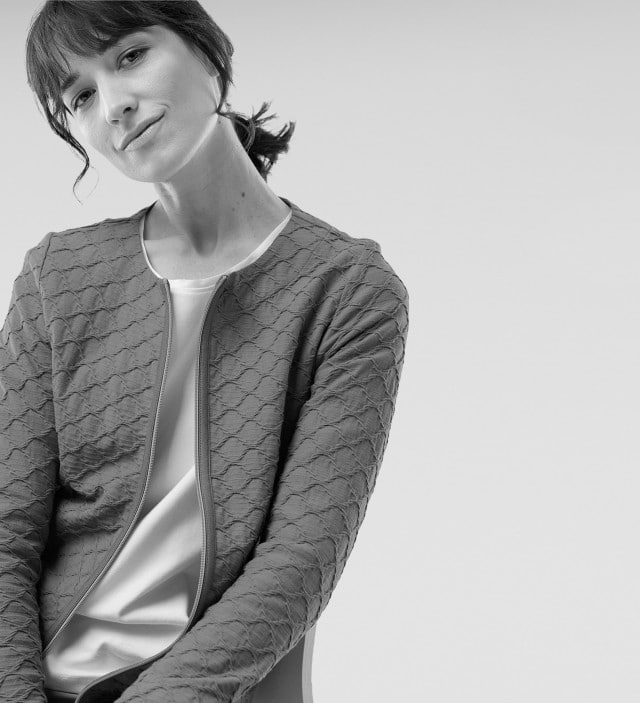Eine Frau trägt einen Strukturblouson mit einem hellen Shirt darunter.