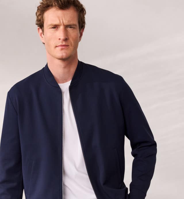 Ein Mann trägt einen Blouson in Marine, darunter ein weißes Shirt.