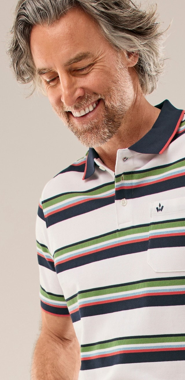 Mann mit gestreiftem Polo steht vor einer Wand
