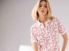 Eine Frau trägt ein weißes Polo-Shirt mit Blumenmuster.