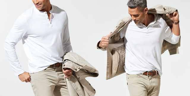 Mann in weißem Langarmshirt und beiger Hose, hält Jacke in der Hand und zieht sie an.