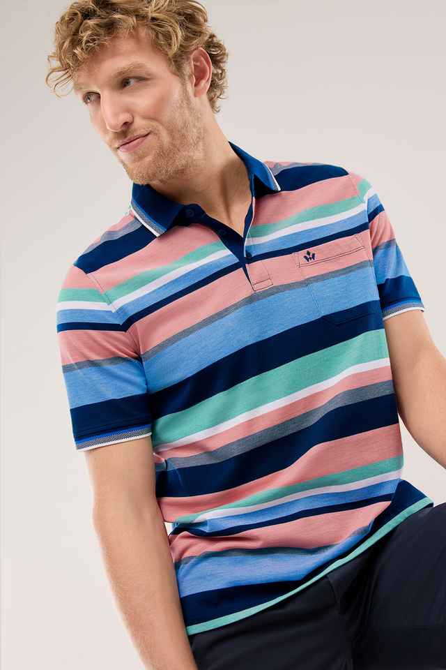 Mann mit lockigem Haar trägt ein bunt gestreiftes Polohemd in Blau, Rosa und Grün und blickt zur Seite.